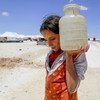 In the makeshift camp at Ain Issa, 50 km north of the Raqqa in the Syrian Arab Republic, Horriya, 12, carries a jerrycan of water (2017).