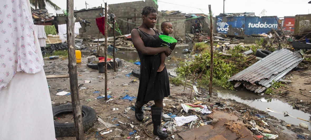 Cecilia Borges carries her son, Fernandino Armindo that is holding a plate, through the destroyed informal settlement, in Beira, Mozambique, on 20 March 2019.