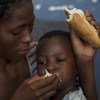 莫桑比克，一位母亲正在一所用作临时安置点的学校内喂她两岁的儿子吃面包。他们在布齐的家被热带气旋“伊代”和随之而来的洪水毁于一旦。