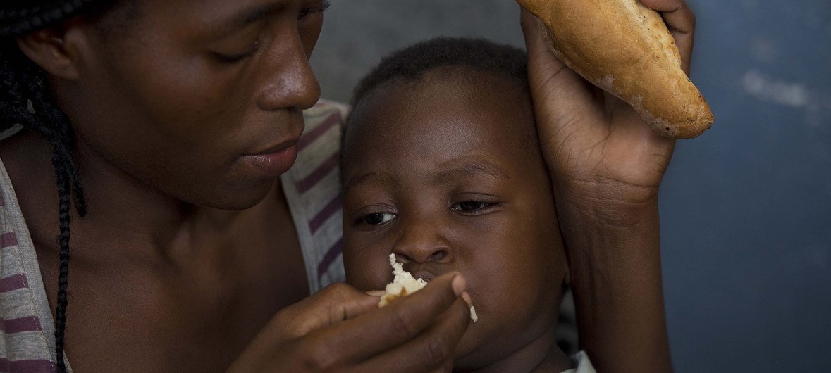 Mãe alimenta filho de dois anos na Escola Samora Machel, que está servindo de abrigo