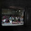 A travers l'ouverture d'une porte en fer, des migrants sont assis sur des matelas posés à même le sol dans un centre de détention en Libye.