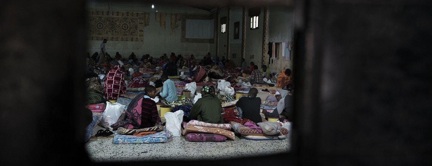 Des migrants sont assis sur des matelas posés à même le sol dans un centre de détention situé en Libye.