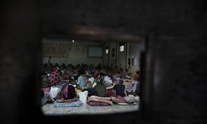 Derrière cette porte en fer, des migrants sont assis sur des matelas posés à même le sol dans un centre de détention en Libye.