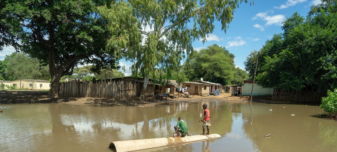 Dos jóvenes juegan en una enorme piscina creada por las inundaciones del ciclón Idai en un campamento de refugidos en Zimbabwe.