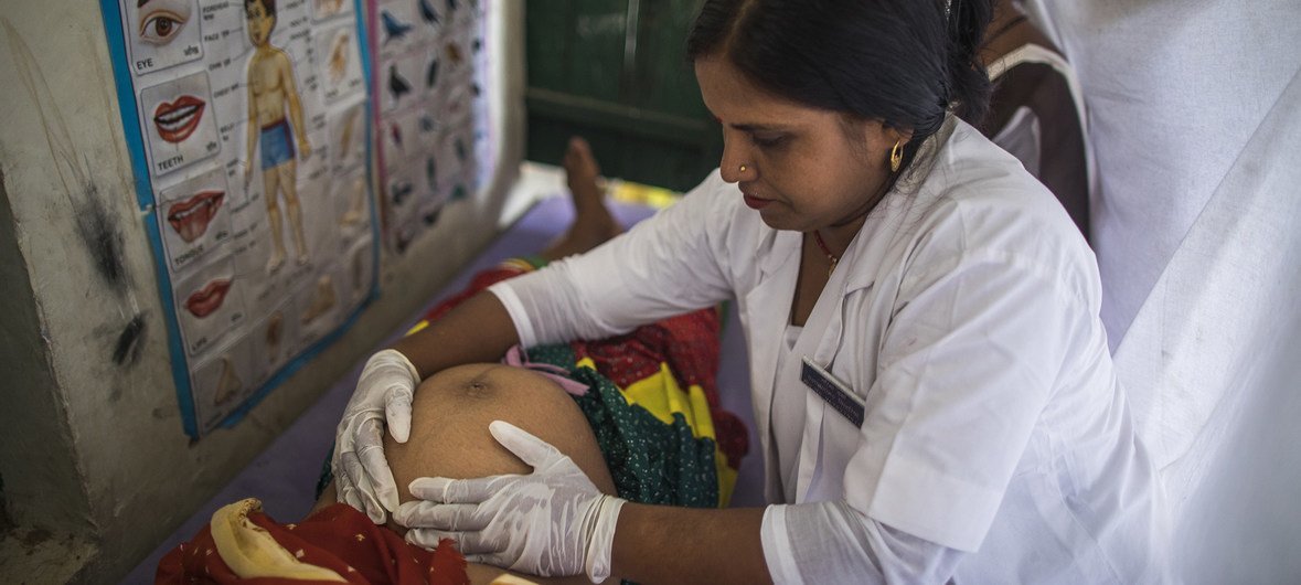 An Auxiliary Nurse Midwife counsels a pregnant woman on institutional delivery while she examines her as part of Village Health and Nutrition Day in Shrawasti, India