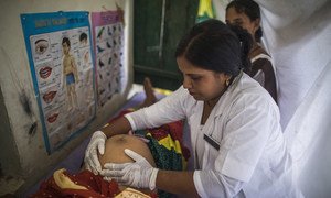 Une sage-femme conseille une femme enceinte lors d'un accouchement en établissement pendant qu'elle l'examine dans le cadre de la Journée de la santé et de la nutrition au village de Shrawasti, en Inde.