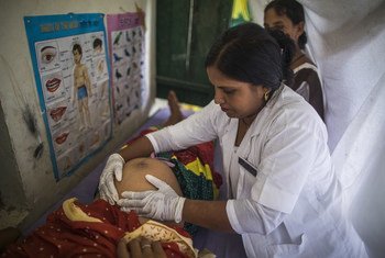 Une sage-femme conseille une femme enceinte lors d'un accouchement en établissement pendant qu'elle l'examine dans le cadre de la Journée de la santé et de la nutrition au village de Shrawasti, en Inde.