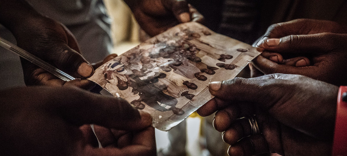 A family internally displaced from Baga to Maiduguri Displacement Camp, Nigeria, touch an old family photo, a reminder of better times.