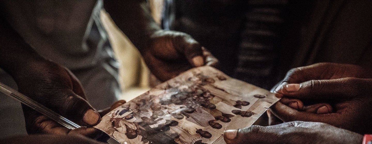 A family internally displaced from Baga to Maiduguri Displacement Camp, Nigeria, touch an old family photo, a reminder of better times.