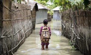 A child wades through water on her way to school in Kurigram district of northern Bangladesh during floods in August 2016.