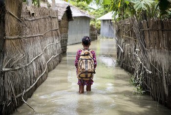 बांग्लादेश के कुरीग्राम ज़िले में एक बच्चा बाढ़ प्रभावित इलाक़े से होकर स्कूल जाते हुए. यह फ़ोटो बांग्लादेश में अगस्त 2016 में आई बाढ़ के दौरान लिया गया था.