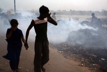 बांग्लादेश की राजधानी ढाका में जलते कूड़े के ढेर के पास से गुज़रते लोग.