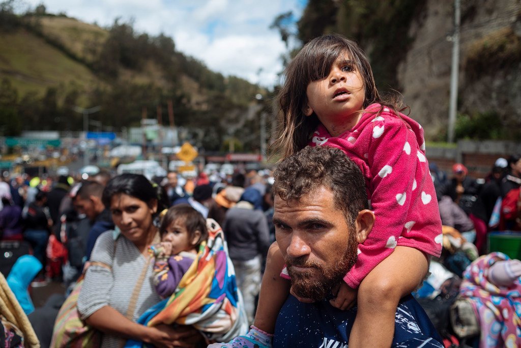 三岁的莱拉·达利拉·莱昂坐在父亲的肩膀上，看着厄瓜多尔与哥伦比亚交界的鲁米查卡的哥伦比亚海关(2018年8月9日)。