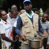 Un homme portant un gilet de la Croix-Rouge tient une marmite pour un groupe de personnes dans la province de Manica, au Mozambique, lors d'une mission de soutien aux efforts de secours suite au cyclone Idai.