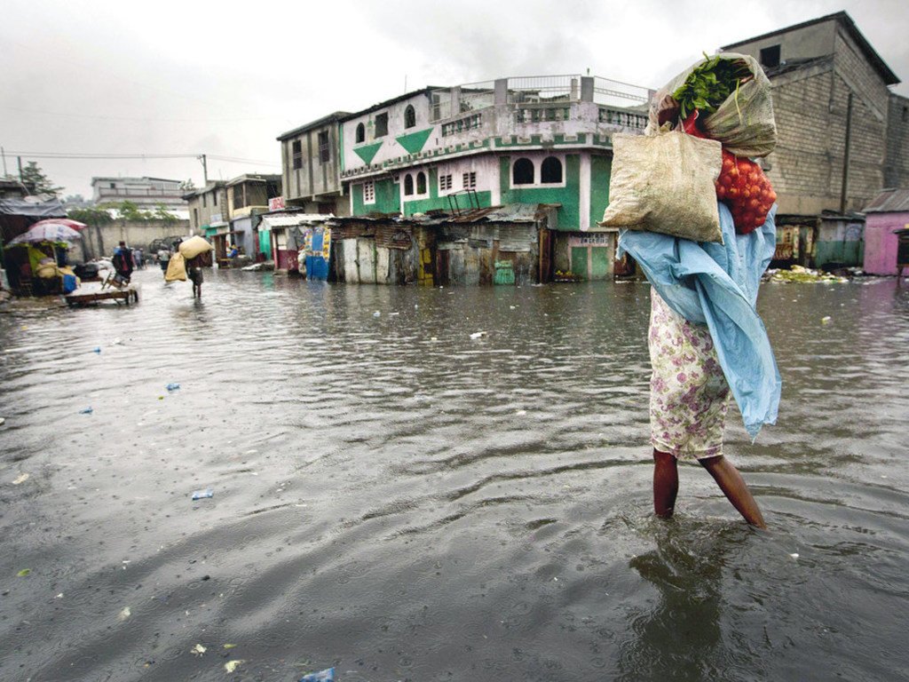 一名妇女走过海地太子港的一个被水淹没的市场，飓风“桑迪”2012年对加勒比海岛屿国家造成了严重破坏。