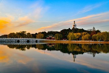 黄昏时分的北京北海公园，琼华岛上的白塔倒映在湖心。