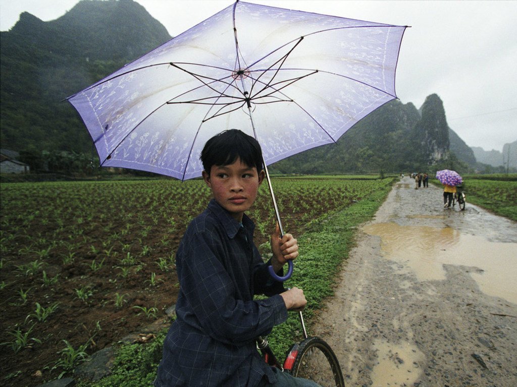 中国西南地区的学生在雨天里骑车上学。