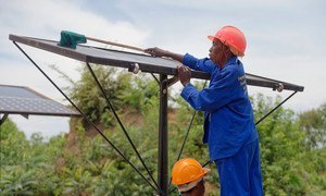 Emmery Matongo, construction and solar panel trainee, cleaning the solar panels installed and assembled by local women as part of the Zambia Green Jobs Programme led by the ILO. (2015)