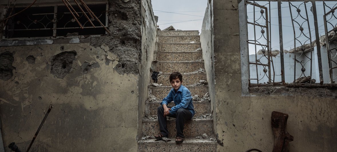 Mohammed, 10, sits on the staircase of the former house he used to hide with his family in Mosul.