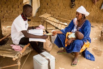 A mother in the remote village of Kombaka in Mali is handed a vaccination card after her child received an immunization administered by a health worker. (March 2019)