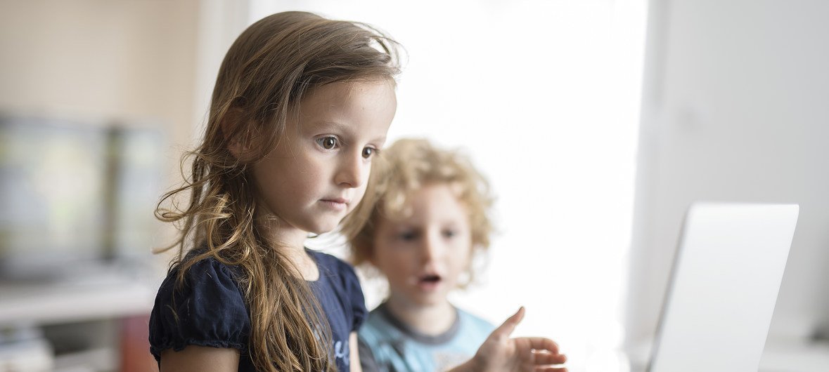 Uma criança de 6 anos e outra de 4 anos são fotografadas em frente a um laptop, na cidade de Podgorica, Montenegro, como parte da promoção da campanha “End Violence Online” (2016)