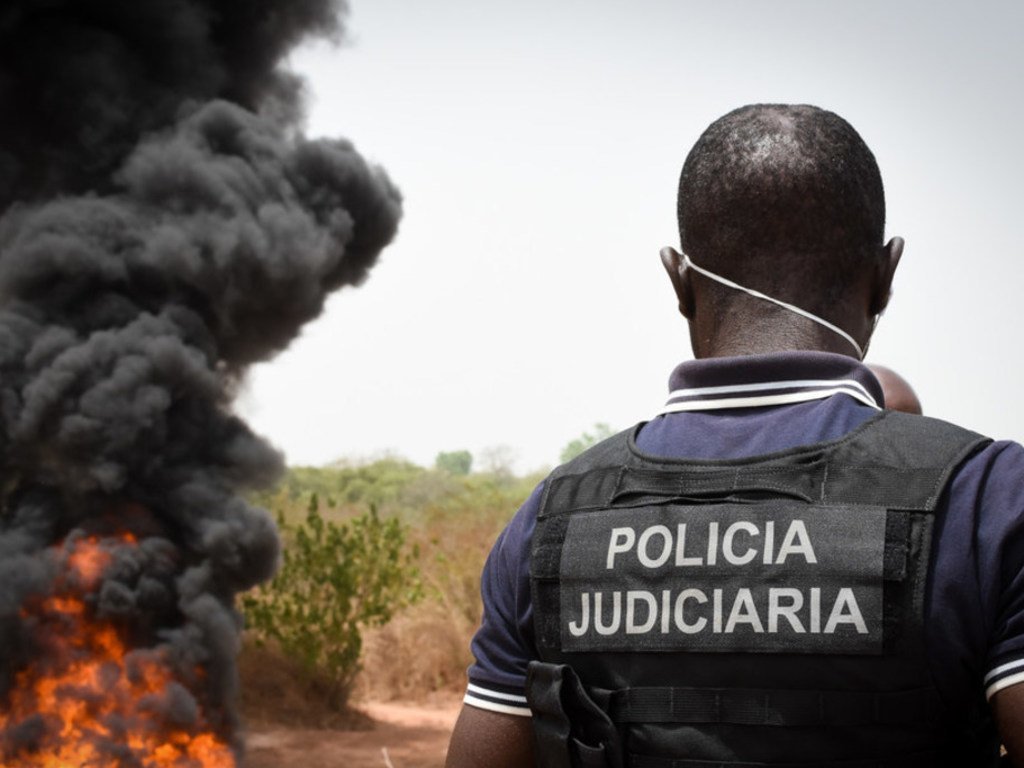 Un agente de policía observa la quema de sustancias ilícitas en Guinea-Bissau.