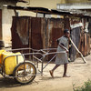 一名贝宁儿童正用推车和水罐取水。