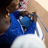 Femme en haut bleu tissant un tissu bleu à partir de fil de plastique.