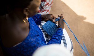 Au Burkina Faso, un membre du groupe NEERE tisse à la main un petit sac bleu en plastique dans le cadre d'une initiative visant à soutenir la création de revenus pour les femmes et les jeunes de ce pays d'Afrique de l'Ouest.