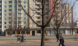 Children and adults pass a high-rise apartment building in Pyongyang, DPRK.