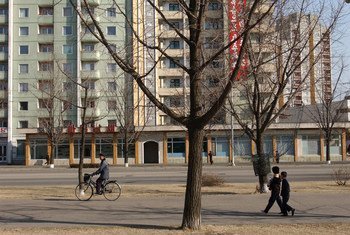 Children and adults pass a high-rise apartment building in Pyongyang, DPRK.