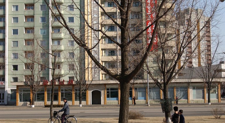 朝鲜儿童和成人经过首都平壤的一栋高层公寓楼。 2004年7月，城市住宅中的电力和水短缺十分普遍。