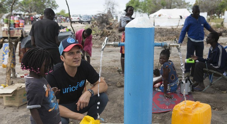  Orlando Bloom ajuda uma criança a encher um galão cheio de água da Unicef no local de reassentamento de Mendruzi para pessoas deslocadas pelos recentes ciclones.