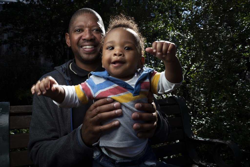 Bongani Ngqame在南非开普敦他在卫生局的办公室附近的公园里与他8个月大的儿子Khuma一起照相。