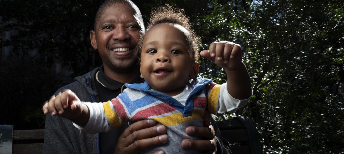 दक्षिण अफ्रीका के केपटाउन में एक पिता बोनगामी नकेम अपने आठ महीने के बच्चे - खूमा के साथ