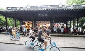 Youth riding share bikes along the UNESCO World Heritage Site West Lake in Hangzhou, China.