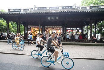 Youth riding share bikes along the UNESCO World Heritage Site West Lake in Hangzhou, China.