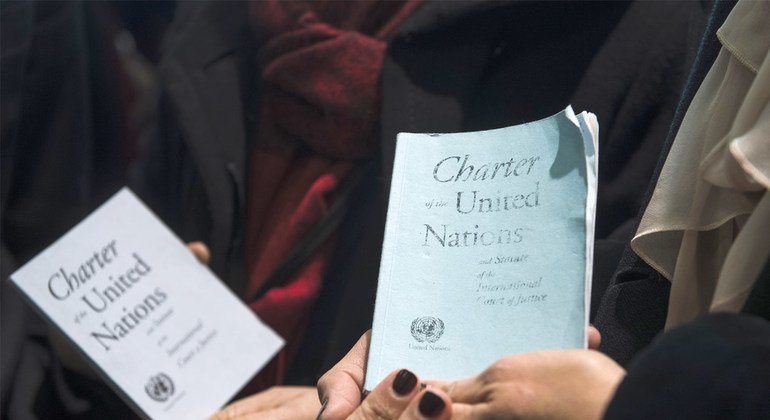 Participantes de um evento na ONU seguram cópias da Carta das Nações Unidas