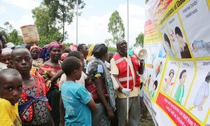 A Uganda Red Cross volunteer teaches people about dangers of Ebola using a banner provided by UNICEF as people from Democratic Republic arrive at a screening facility set up at point of entry at Uganda-DRC border town of Bunagana in Kisoro district.