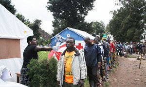 A health worker takes the temperature of a man as people from the Democratic Republic of the Congo line up at a screening facility set up at point of entry at a Uganda-DRC border town.  Medical staff routinely check people who enter Uganda from the DRC fo