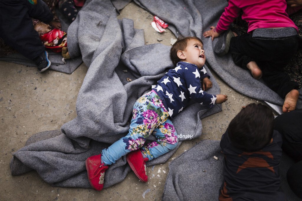 (من الأرشيف) فتاة صغيرة مستلقية على بكانية في منتصف الطريق، بالقرب من إحدى محطات العبور في اليونان، حيث أن هناك الآلاف من اللاجئين والمهاجرين على الرغم من إغلاق ما يسمى "طريق غرب البلقان".