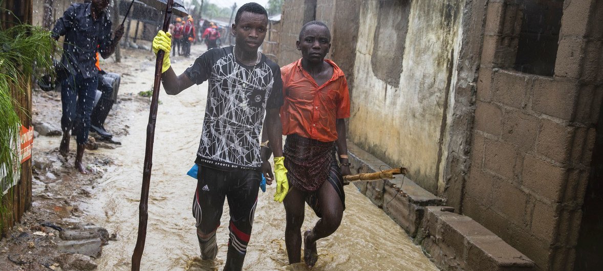 Deux jeunes hommes marchent dans une zone inondée dans la région de Pemba, au Mozambique (avril 2019).