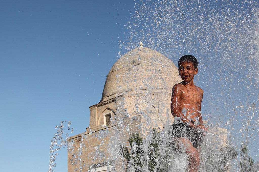  为了在夏天避暑，乌兹别克斯坦一名11岁的男孩在撒马尔罕市历史悠久的喷泉中玩耍。 （资料）