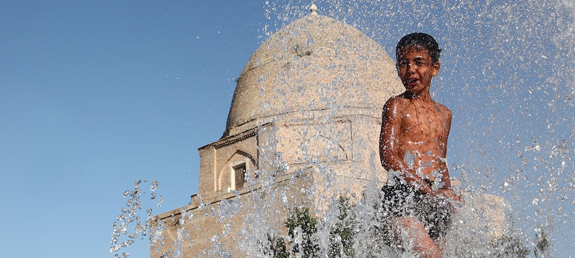 गर्मी से राहत पाने के लिए, 11 साल का एक लड़का, उज़्बेकिस्तान के समरकंद शहर के एक ऐतिहासिक हिस्से में फव्वारे में खेल रहा है. (फाइल)