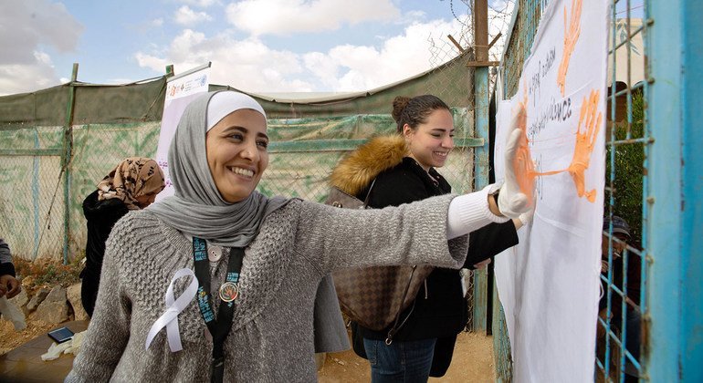 السيدة روان المجالي، من مخيم الزعتري للاجئين في الأردن، تشارك بحملة لا للعنف ضد المرأة وتطبع بصمة يديها باللون البرتقالي على الملصق تعبيرا عن رفضها للعنف. (من الأرشيف)