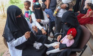 A health worker in Aden, Yemen, fills a needle as she prepares to vaccinate a young gild during a UNICEF-backed Measles and Rubella vaccination campaign in February 2019.