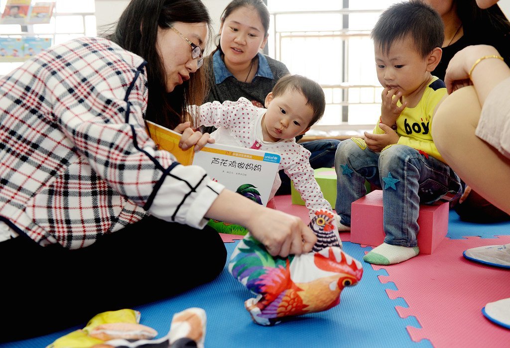 2015年4月，在湖北省襄阳市的一所由联合国儿童基金会提供支持的社区儿童早期发展中心里，志愿者给孩子们讲故事。