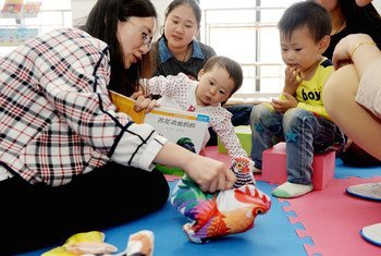 2015年4月，在湖北省襄阳市的一所由联合国儿童基金会提供支持的社区儿童早期发展中心里，志愿者给孩子们讲故事。
