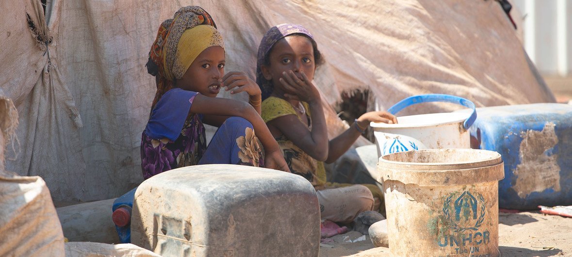 Niños sentados frente a una casa de campaña en el campamento para desplazados de Al-Meshqafah en Yemen.