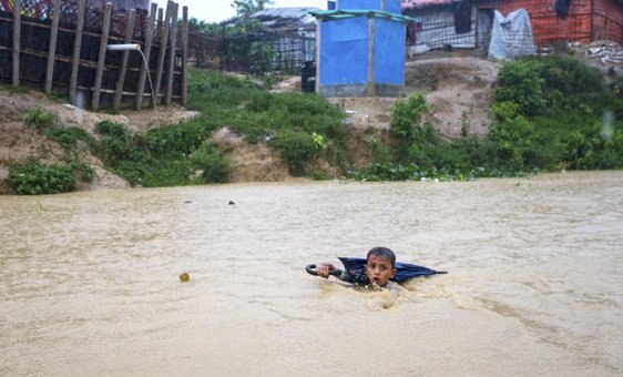 A young boy in Bangladesh navigates a river swollen from days of monsoon rain. He is collecting plastic bottles washed into the river to sell to recyclers to help his family purchase food.